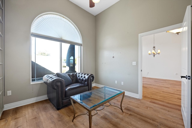 living room featuring vaulted ceiling, light hardwood / wood-style floors, and ceiling fan with notable chandelier