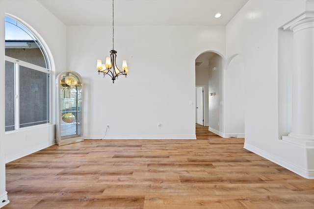 unfurnished dining area featuring a chandelier, a high ceiling, and light wood-type flooring