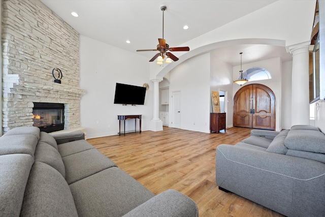 living room with hardwood / wood-style flooring, ceiling fan, a fireplace, and a high ceiling