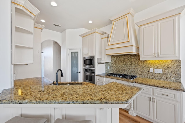 kitchen with custom exhaust hood, a breakfast bar, sink, decorative backsplash, and appliances with stainless steel finishes