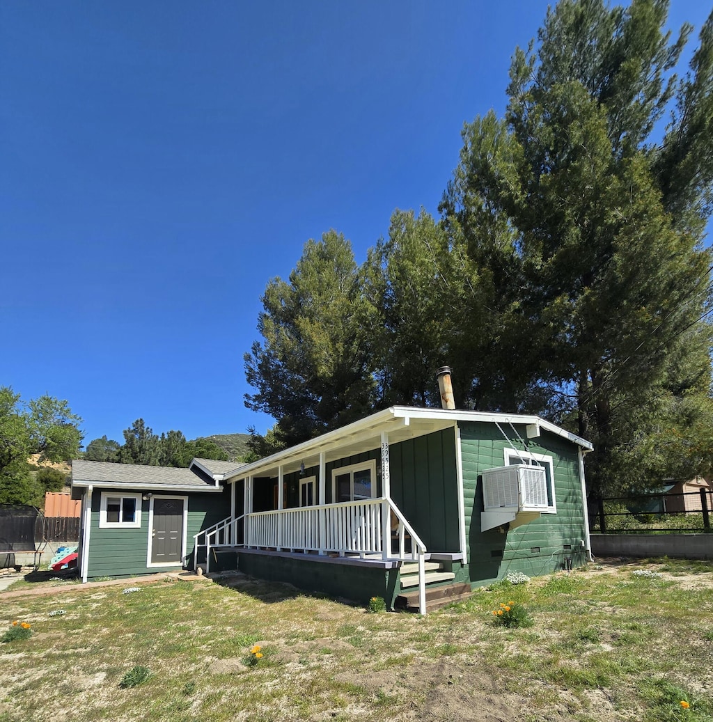 view of front of home with a porch, a front yard, and fence