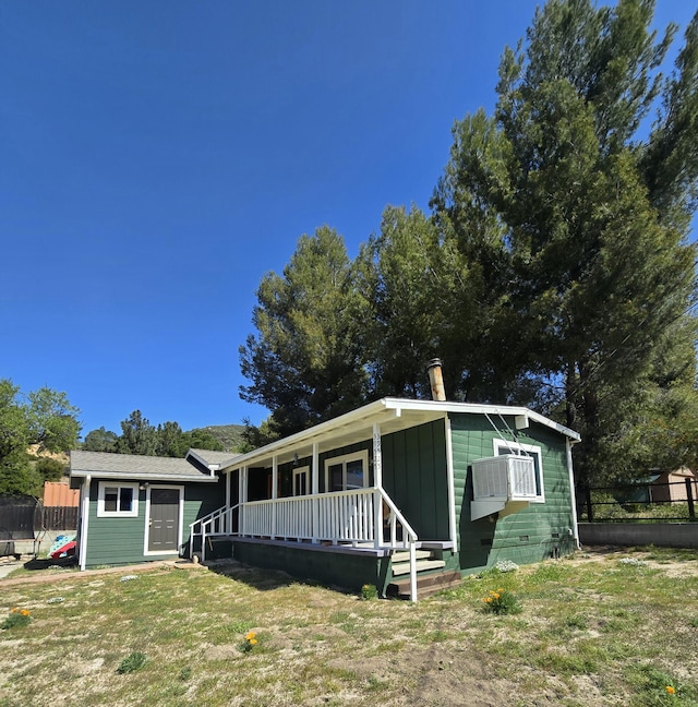 view of front of home with a porch, a front yard, and fence