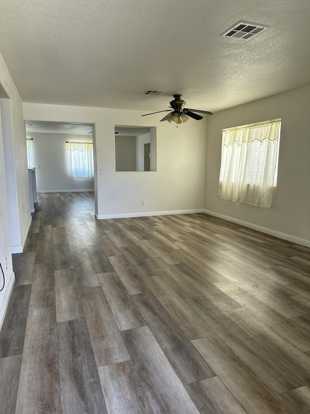 spare room featuring visible vents, dark wood finished floors, and a textured ceiling