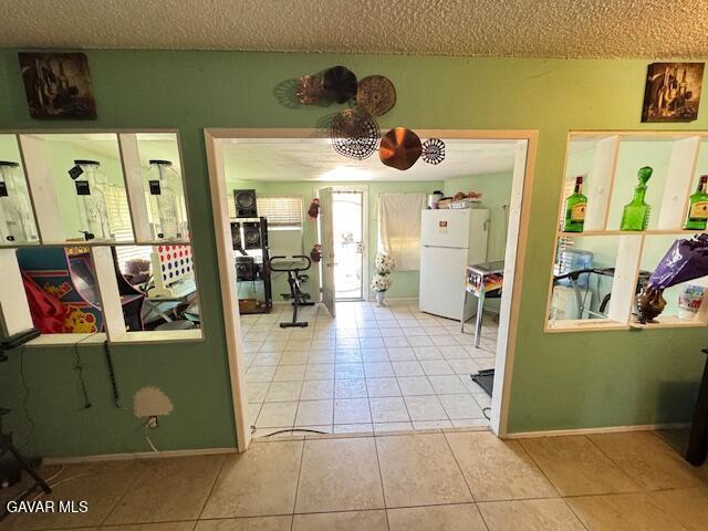45529 Sancroft Ave, Lancaster, CA 93535 - interior space featuring freestanding refrigerator, tile patterned floors, and a textured ceiling