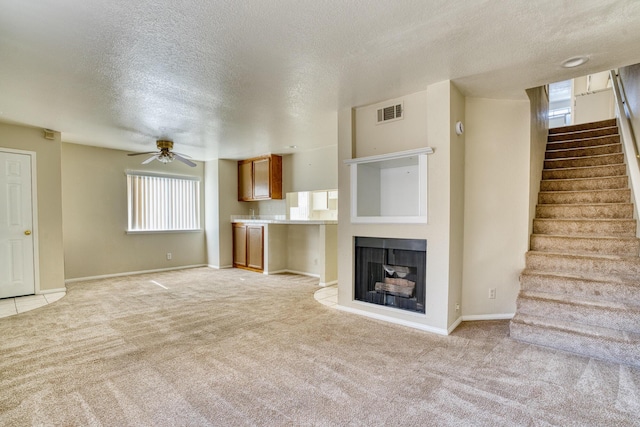 43441 W 30th St Unit 4, Lancaster, CA 93536 - unfurnished living room with light colored carpet, stairway, a textured ceiling, ceiling fan, and baseboards
