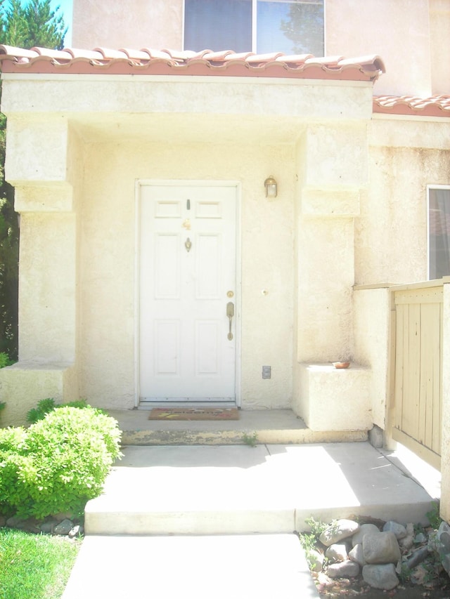 doorway to property with a tiled roof and stucco siding