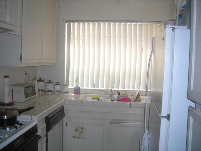 kitchen featuring tile countertops, white appliances, and white cabinetry