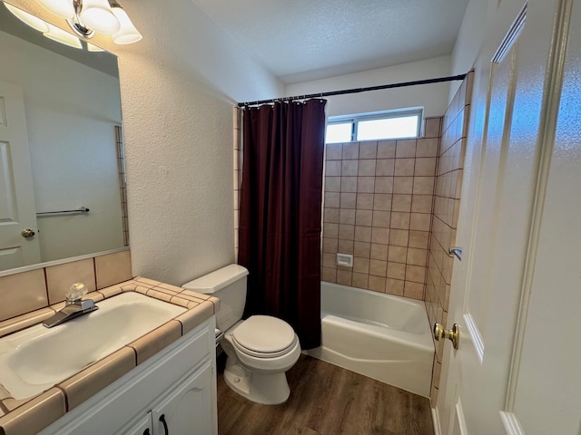 full bathroom featuring hardwood / wood-style floors, vanity, a textured ceiling, toilet, and shower / bath combo with shower curtain