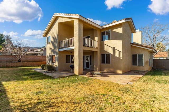 rear view of house with a balcony, a lawn, and a patio area