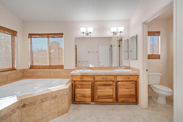 bathroom featuring tiled bath, a chandelier, vanity, toilet, and a healthy amount of sunlight