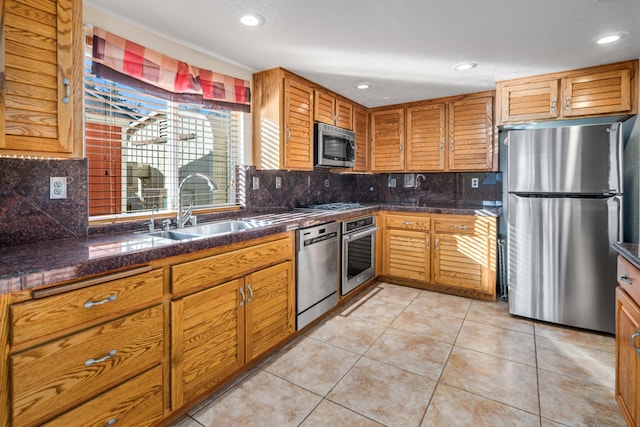 kitchen featuring tasteful backsplash, sink, light tile patterned floors, and stainless steel appliances