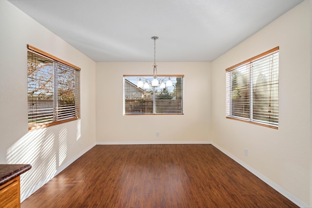 unfurnished dining area with dark wood-type flooring and a notable chandelier