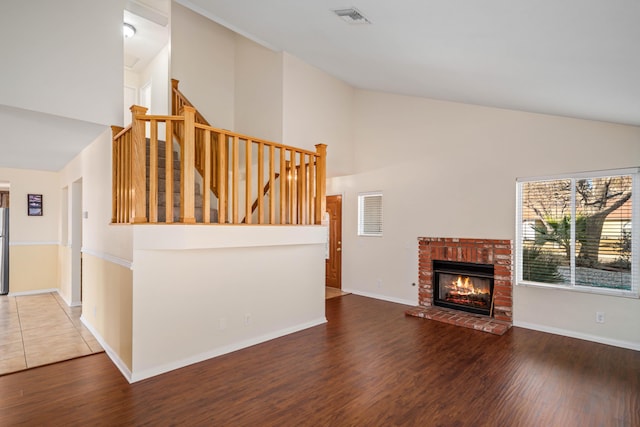 living room featuring dark hardwood / wood-style flooring, vaulted ceiling, and a brick fireplace