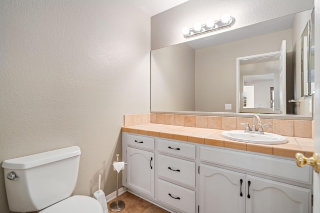 bathroom featuring vanity, toilet, and decorative backsplash