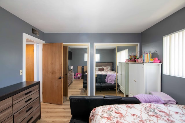 bedroom with light wood finished floors, multiple closets, and multiple windows