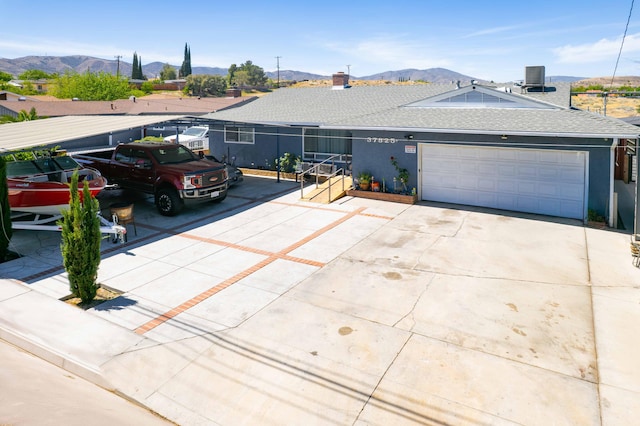 ranch-style home featuring concrete driveway, a mountain view, an attached garage, and central AC