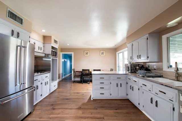 kitchen with a sink, a peninsula, visible vents, recessed lighting, and appliances with stainless steel finishes