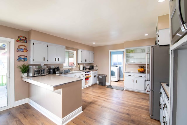 kitchen with baseboards, a healthy amount of sunlight, washer / clothes dryer, and a peninsula