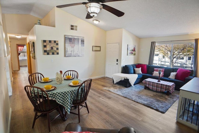 dining room with hardwood / wood-style floors, ceiling fan, a textured ceiling, and vaulted ceiling