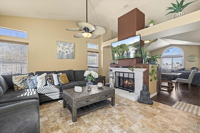 living room with a brick fireplace, lofted ceiling, and ceiling fan