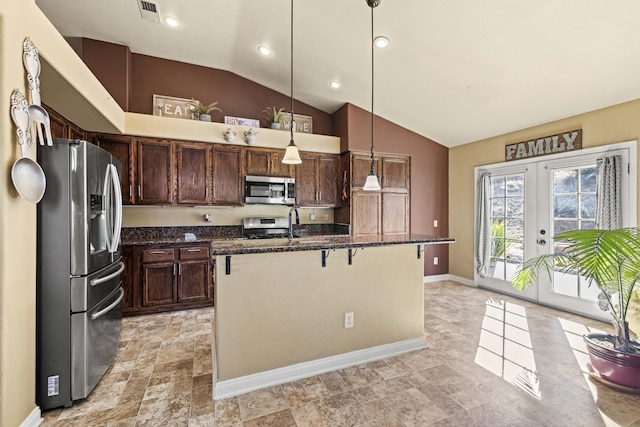 kitchen featuring pendant lighting, stainless steel appliances, french doors, a kitchen island with sink, and a breakfast bar