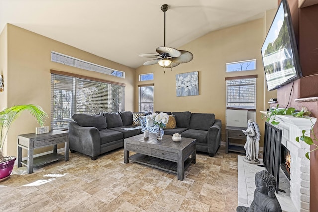 living room featuring ceiling fan, a brick fireplace, and lofted ceiling