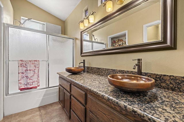 bathroom with vanity, vaulted ceiling, combined bath / shower with glass door, and tile patterned flooring