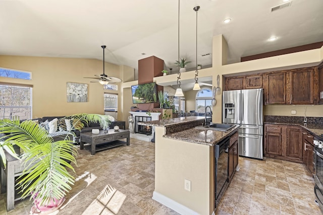 kitchen featuring decorative light fixtures, sink, stainless steel appliances, and dark stone counters