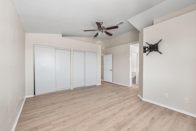 unfurnished bedroom featuring multiple closets, ensuite bathroom, ceiling fan, and light wood-type flooring