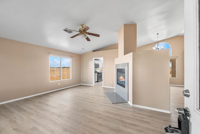 unfurnished living room with a tile fireplace, vaulted ceiling, and light hardwood / wood-style floors