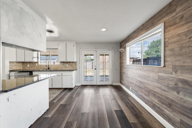 kitchen with white cabinets, backsplash, wood walls, and french doors