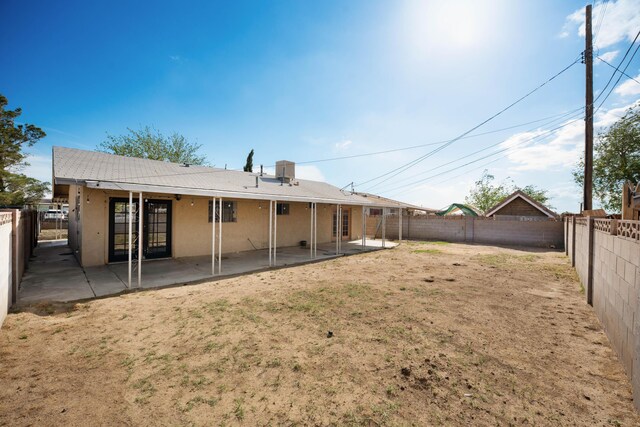 back of house with stucco siding, a fenced backyard, and a patio