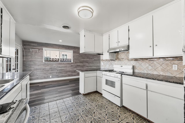 kitchen featuring white cabinets, tasteful backsplash, visible vents, under cabinet range hood, and white gas range