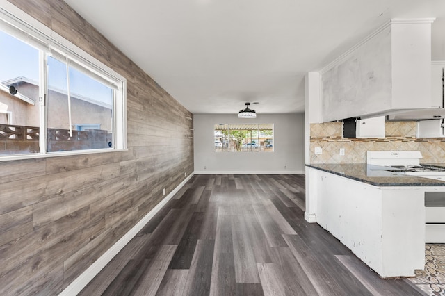 kitchen with gas range gas stove, dark wood finished floors, backsplash, white cabinetry, and under cabinet range hood