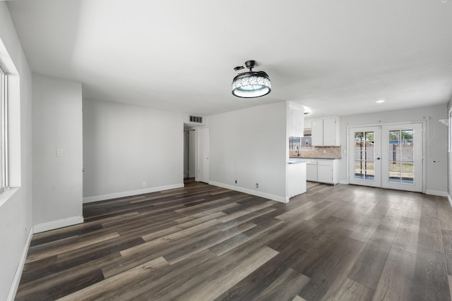 unfurnished living room featuring dark wood-style floors, baseboards, french doors, and visible vents