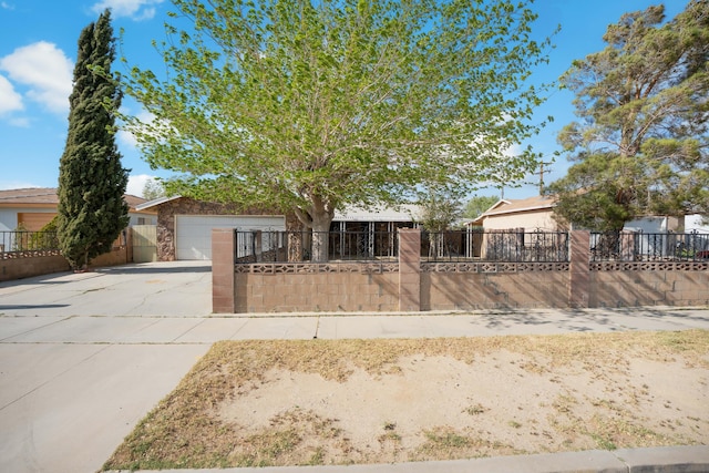 obstructed view of property featuring stone siding, an attached garage, driveway, and a fenced front yard
