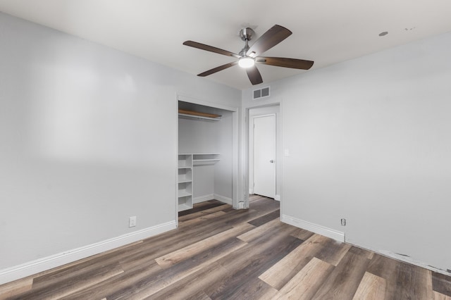 unfurnished bedroom with baseboards, wood finished floors, visible vents, and a closet