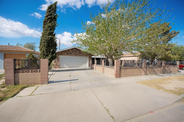 single story home featuring concrete driveway, an attached garage, stone siding, and a fenced front yard