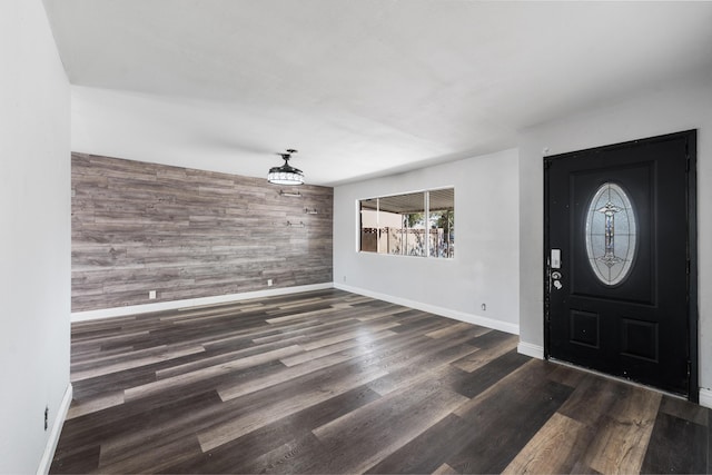 foyer entrance with wood finished floors, wooden walls, baseboards, and an accent wall