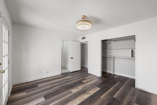 unfurnished bedroom featuring a closet, wood finished floors, visible vents, and baseboards