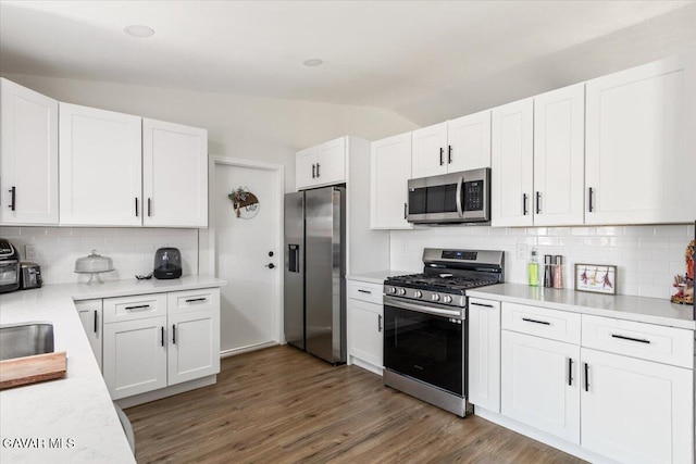 8649 Tamarack Ave, California City, CA 93505 - kitchen with stainless steel appliances, decorative backsplash, white cabinetry, light countertops, and lofted ceiling