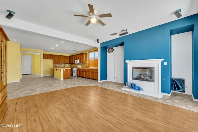 2407 Bavarian Ave, Rosamond, CA 93560 - unfurnished living room featuring ceiling fan, recessed lighting, light wood-type flooring, and a glass covered fireplace