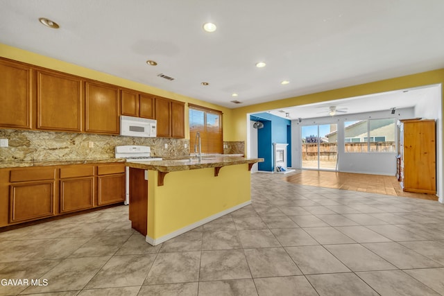 2407 Bavarian Ave, Rosamond, CA 93560 - kitchen with white appliances, a ceiling fan, a kitchen bar, plenty of natural light, and recessed lighting