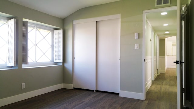 unfurnished bedroom featuring lofted ceiling, visible vents, baseboards, a closet, and dark wood-style floors