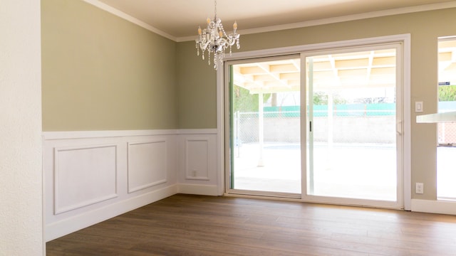 entryway with a notable chandelier, ornamental molding, wood finished floors, and wainscoting