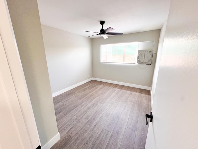 spare room with light wood-type flooring, ceiling fan, and baseboards