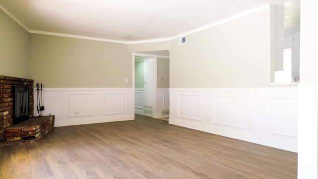 unfurnished living room with a brick fireplace, visible vents, wood finished floors, and ornamental molding