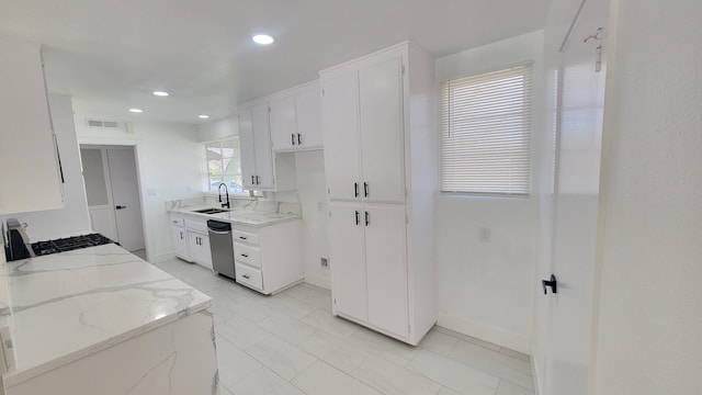 kitchen featuring visible vents, white cabinets, stove, light stone countertops, and a sink