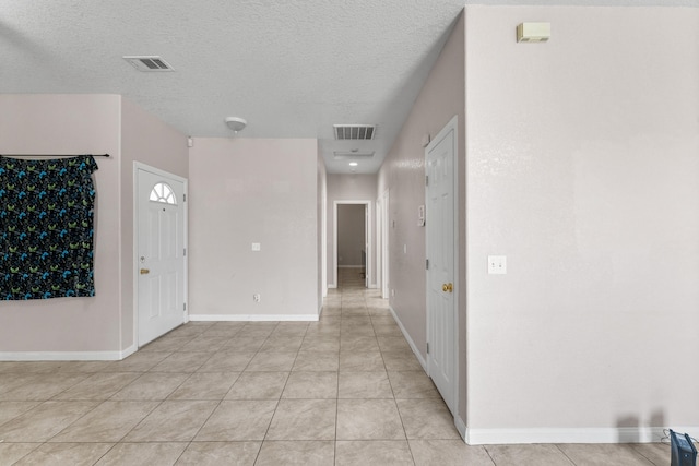 entryway featuring light tile patterned floors and a textured ceiling