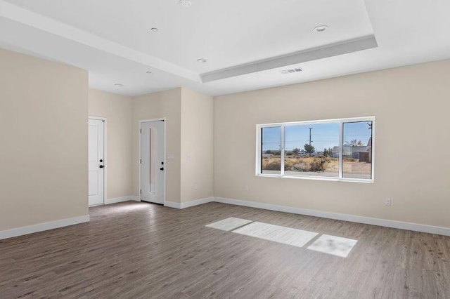 spare room with dark hardwood / wood-style flooring and a tray ceiling